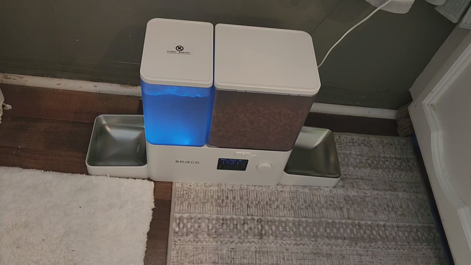 Image of the Rojeco 2-in-1 Automatic Cat Feeder and Water Dispenser featuring a 5L dry food container and a 3.5L gravity water system. The feeder includes stainless steel bowls for hygienic feeding and BPA-free construction to support pet health. The transparent containers allow easy monitoring of food and water levels, while the programmable feeding function enables controlled meal portions throughout the day. LED indicator alerts help ensure consistent food flow, and dual power support (Type-C and AAA bat